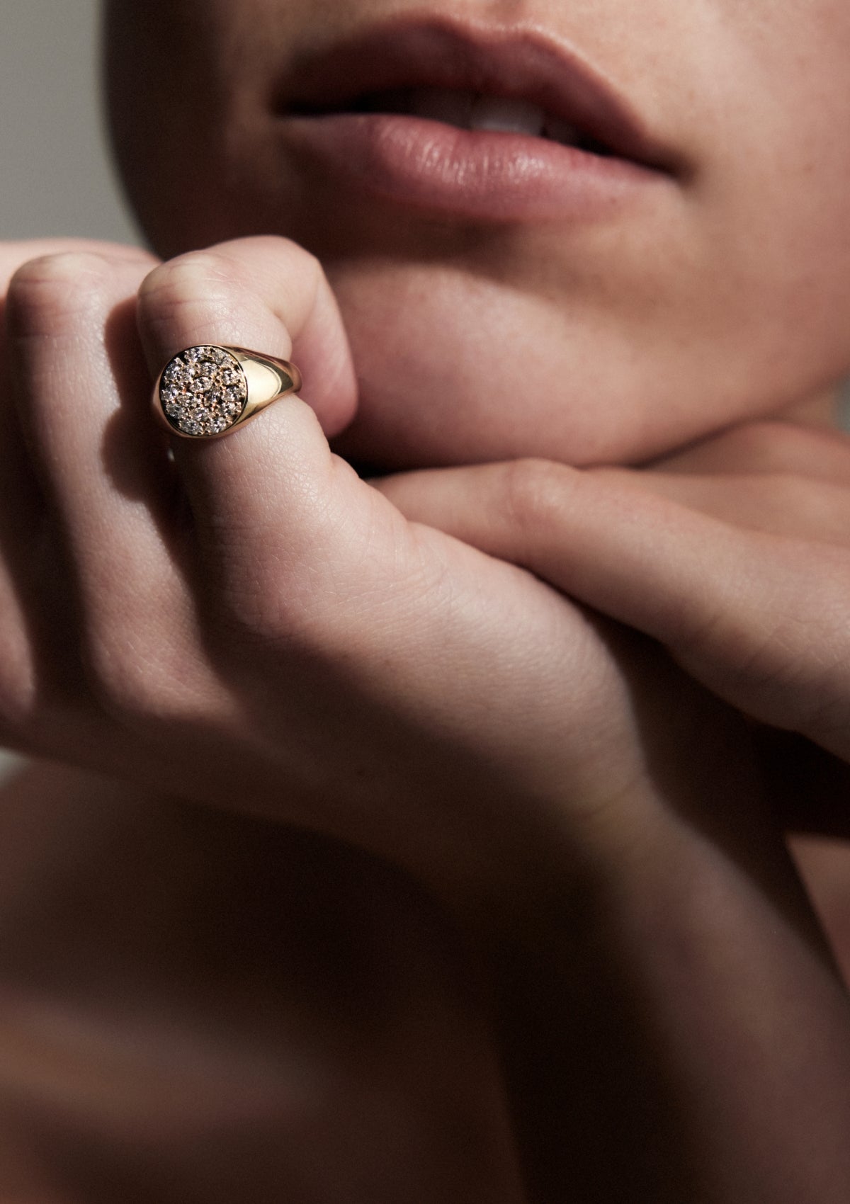 round gold signet with the face covered in closely set marquise diamonds, on a woman's finger, front on, up close