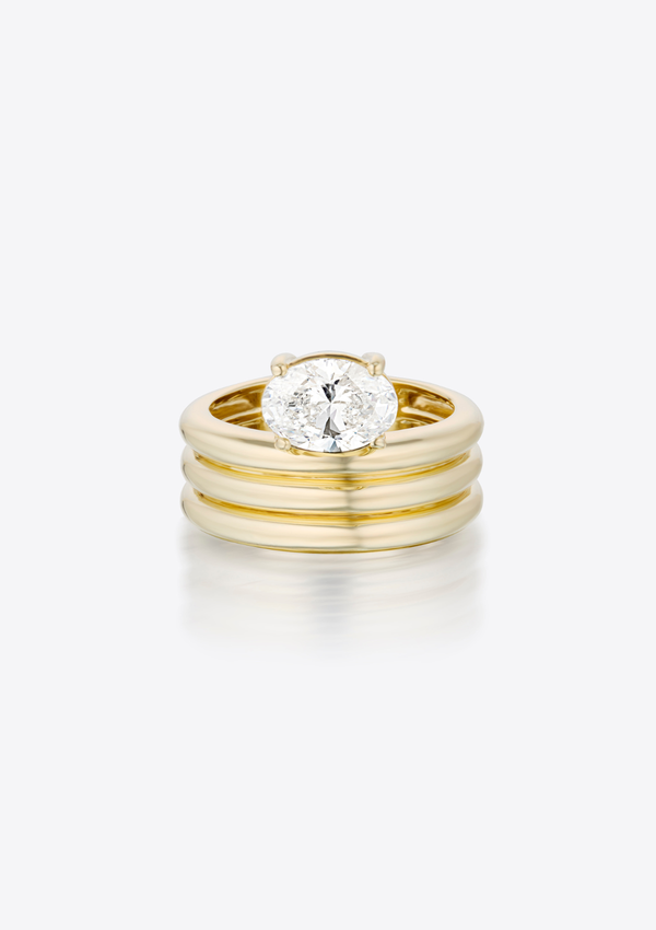 ring with oval diamond sitting above a sculptural, triple ribbed gold thick band. pictured front on, against a grey background