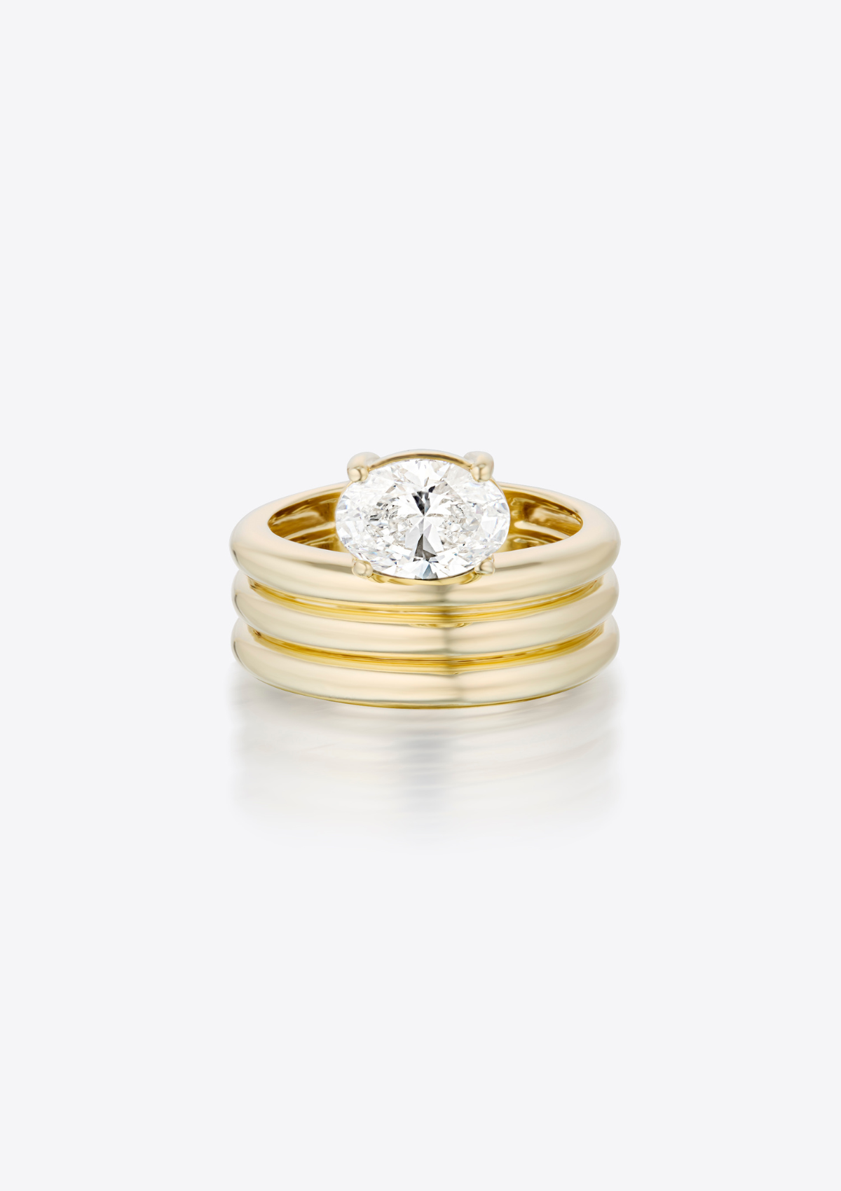 ring with oval diamond sitting above a sculptural, triple ribbed gold thick band. pictured front on, against a grey background