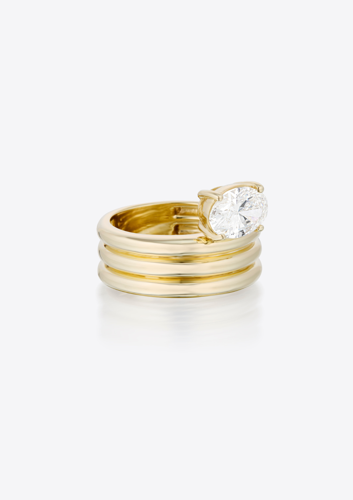 side view of ring with oval diamond sitting above a sculptural, triple ribbed gold thick band. against a grey background