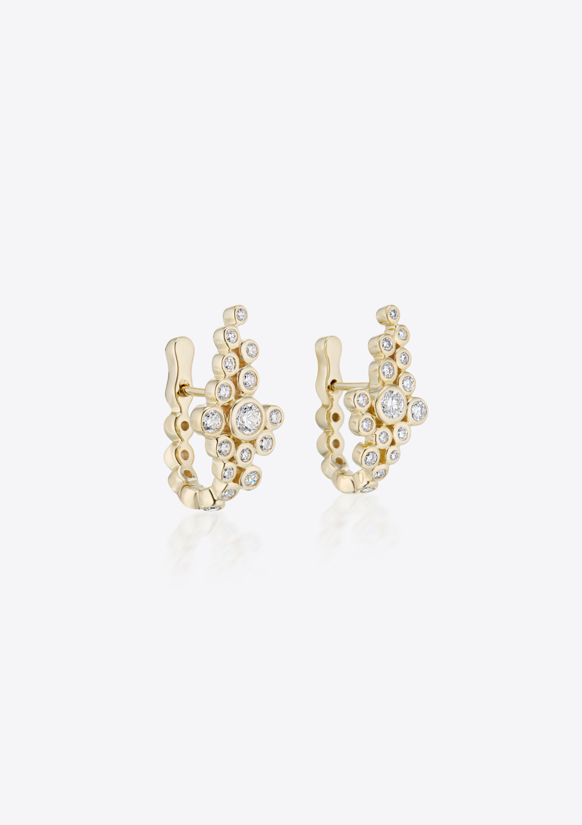 Gold earrings with small round asymmetric diamonds clustered together on a grey background