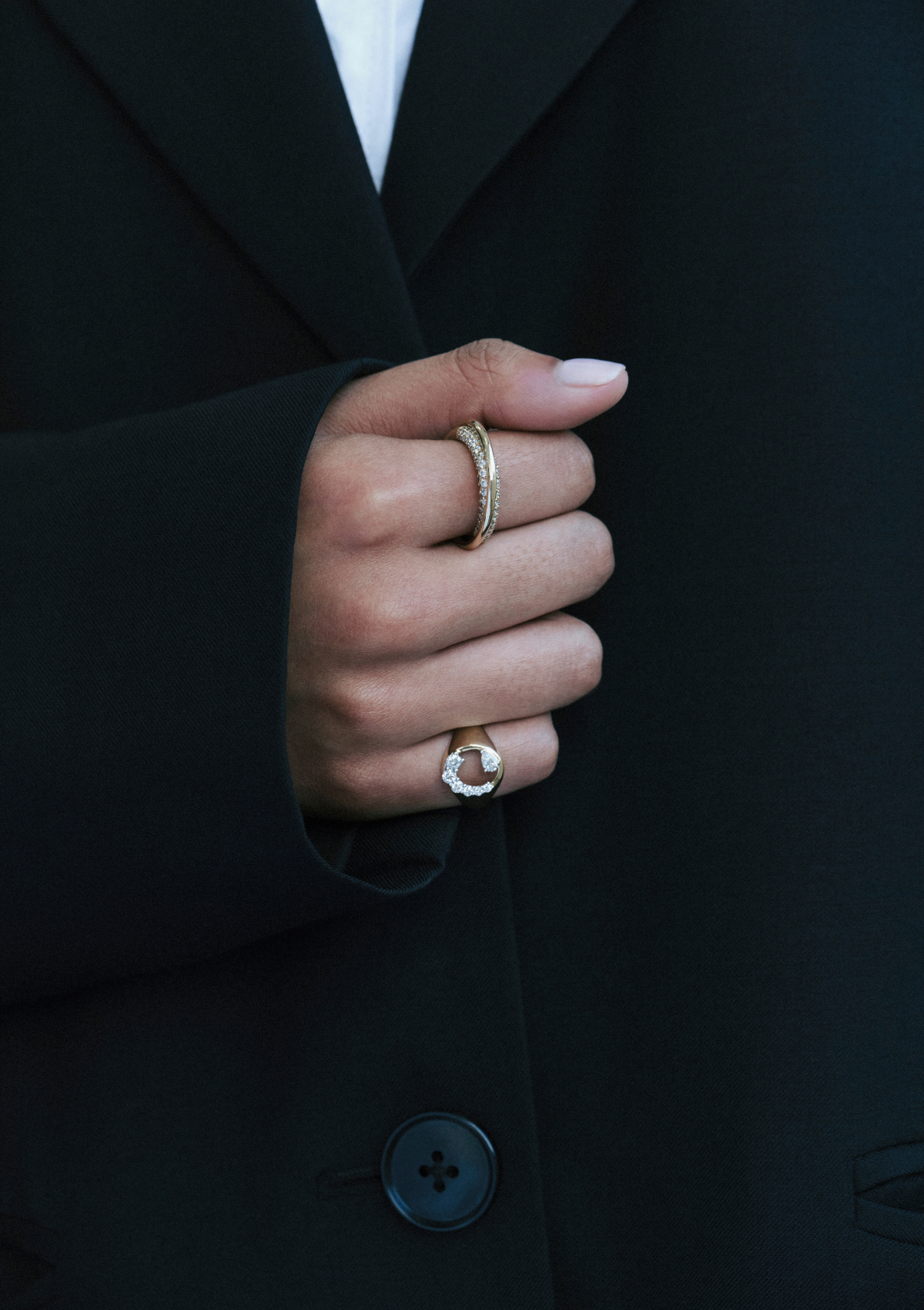 model wearing 2 gold diamond rings, one signet and one pave infinity loop ring
