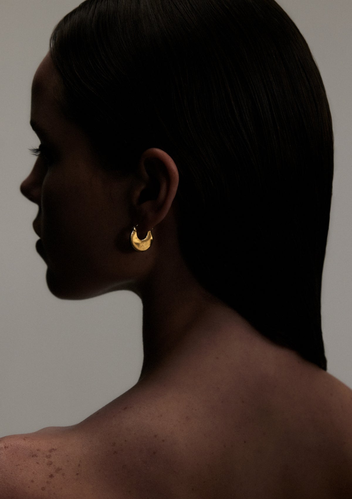 picture of a woman's profile wearing gold solid hoop earrings