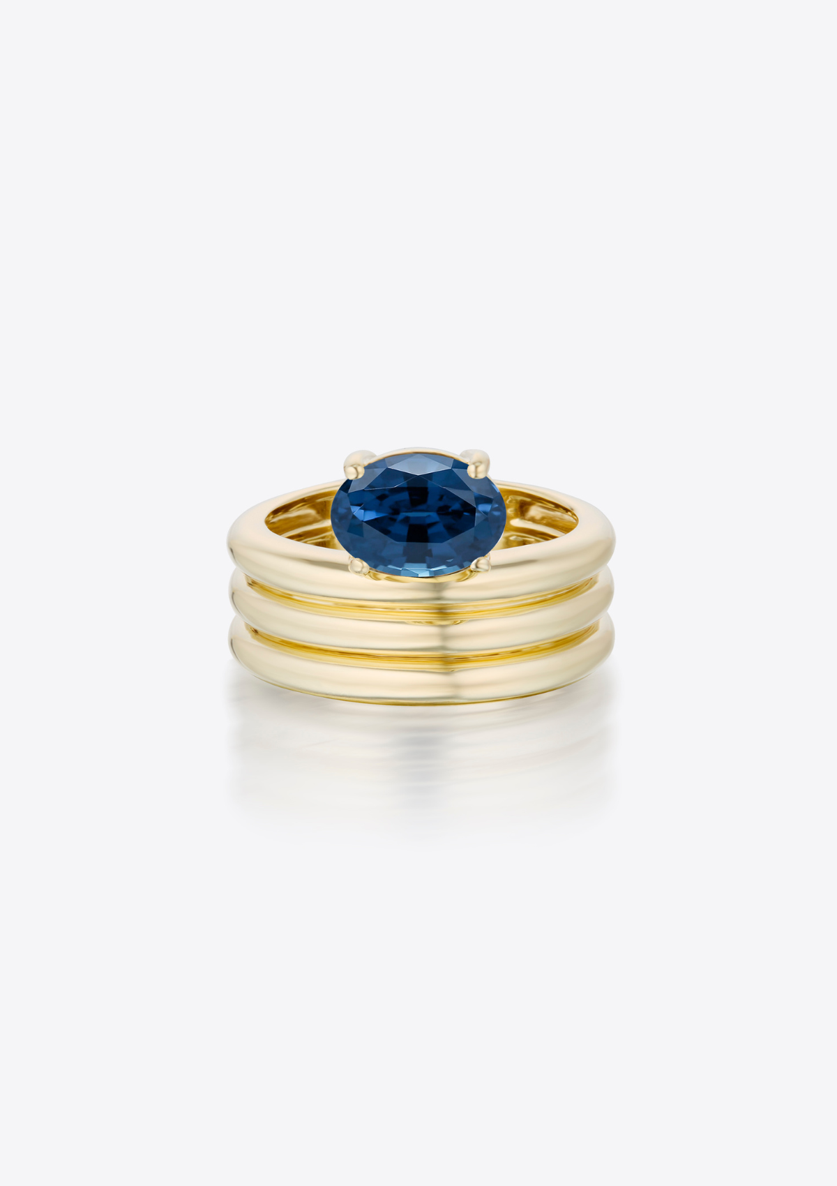 Sculptural Gold ring with a blue oval sapphire on a grey background