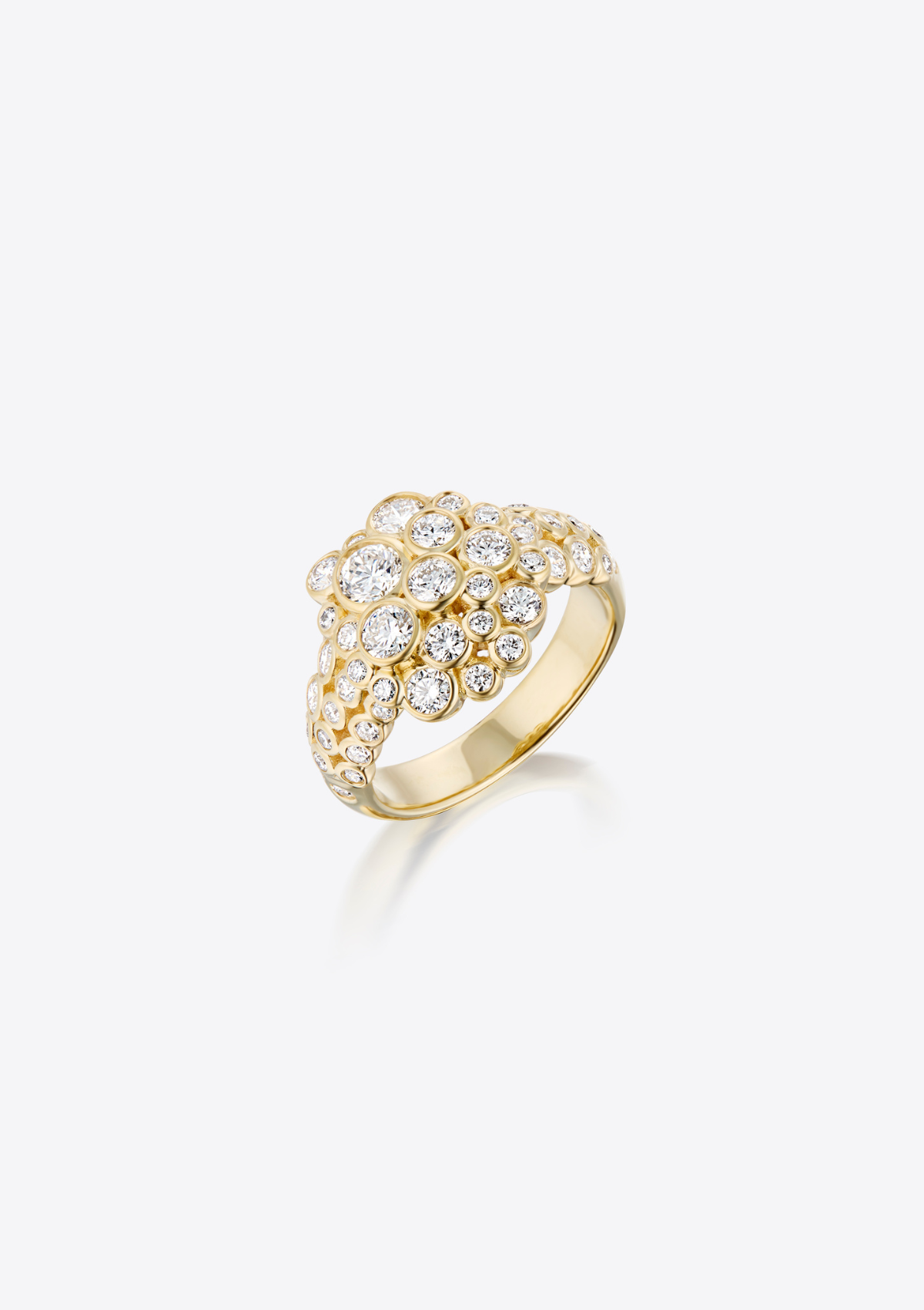 A yellow gold ring featuring a cluster of  different sized diamonds in a sculptural, organic shape, set against a grey background with a soft reflection.