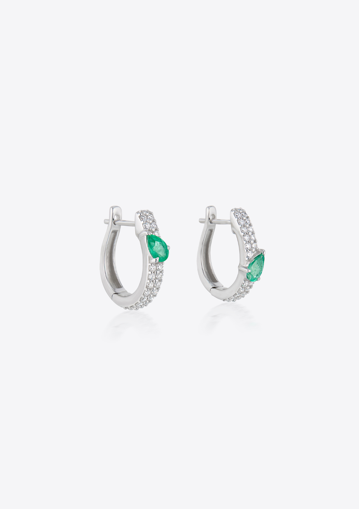 Pair of pave diamond earrings with pear-shaped emeralds asymmetrically positioned. against a grey background
