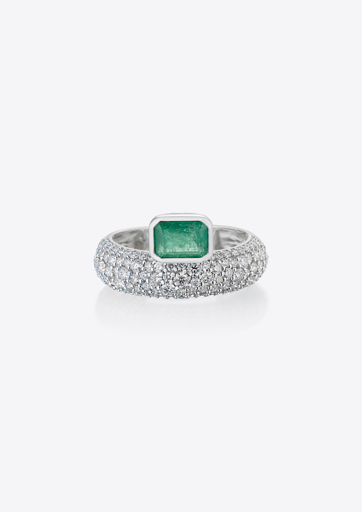 front view of white gold ring with pave diamonds and an emerald sitting on top. on a grey background