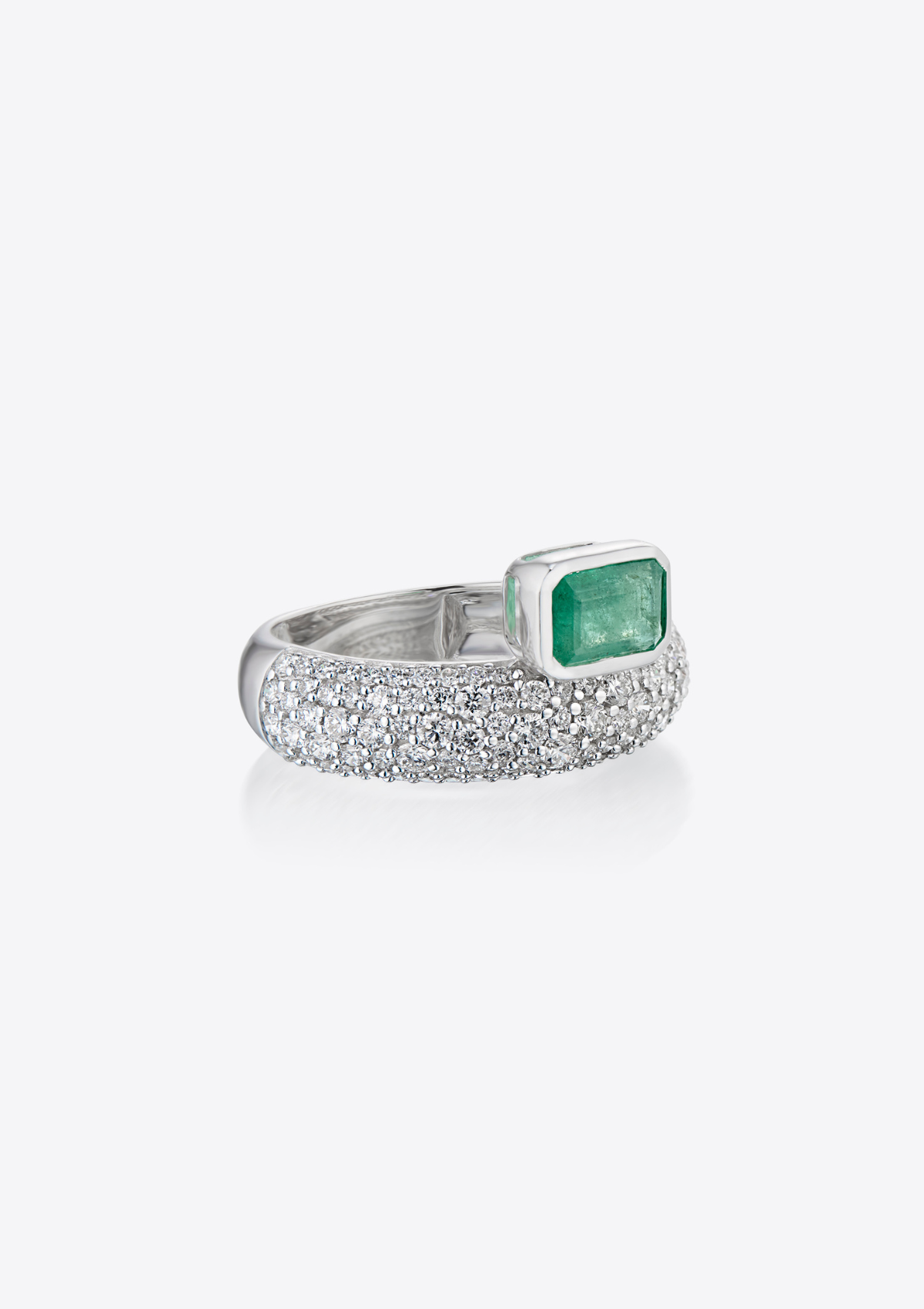 front view of white gold ring with pave diamonds and an emerald sitting on top. on a grey background