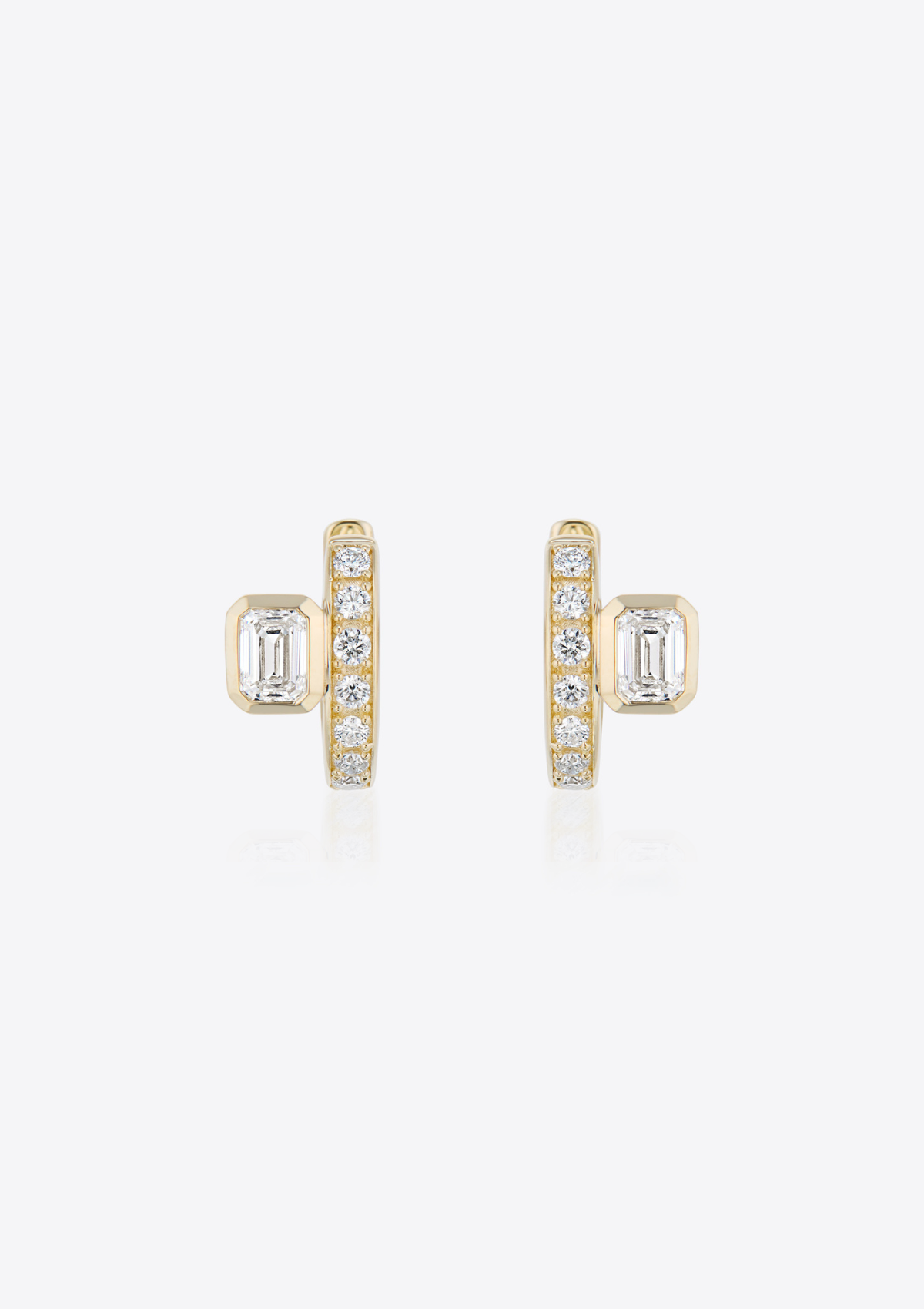 front view of yellow gold diamond huggies with emerald-cut diamonds placed off-centre on grey background