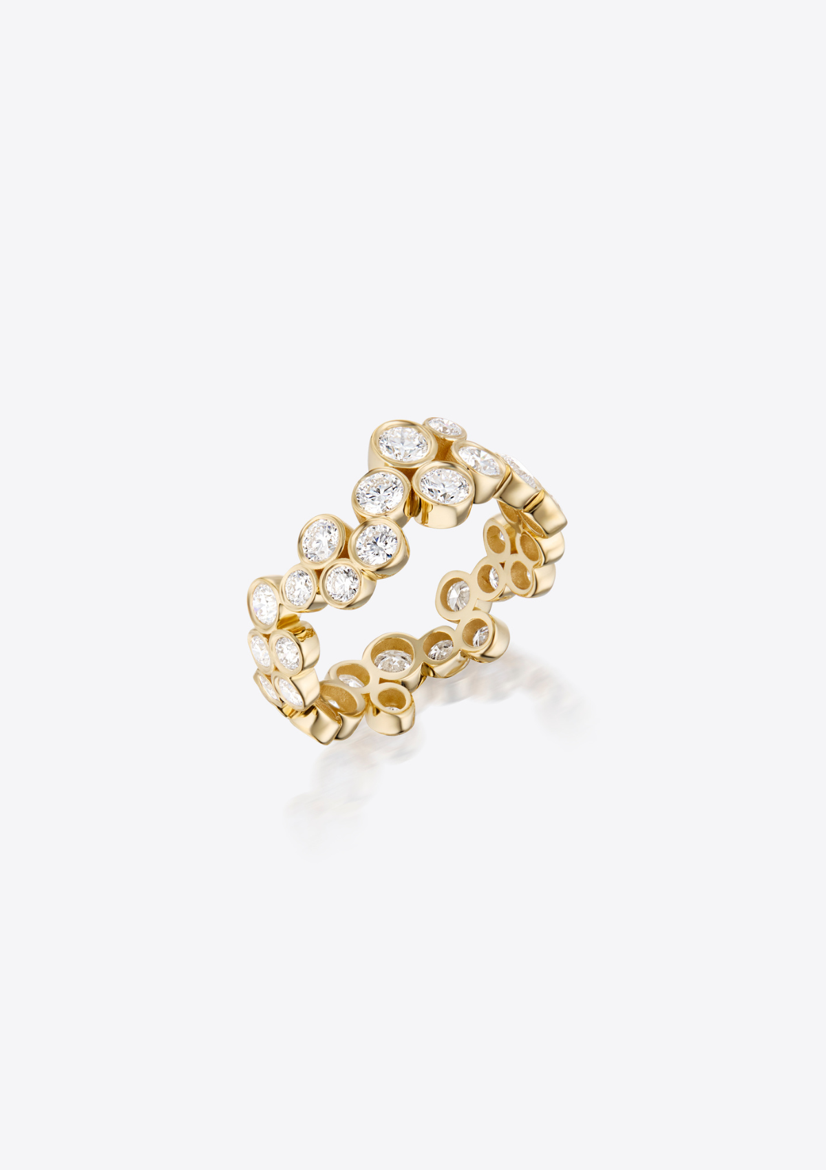 A gold ring tilted upwards featuring a continuous row of randomly placed small round diamonds, on a grey background