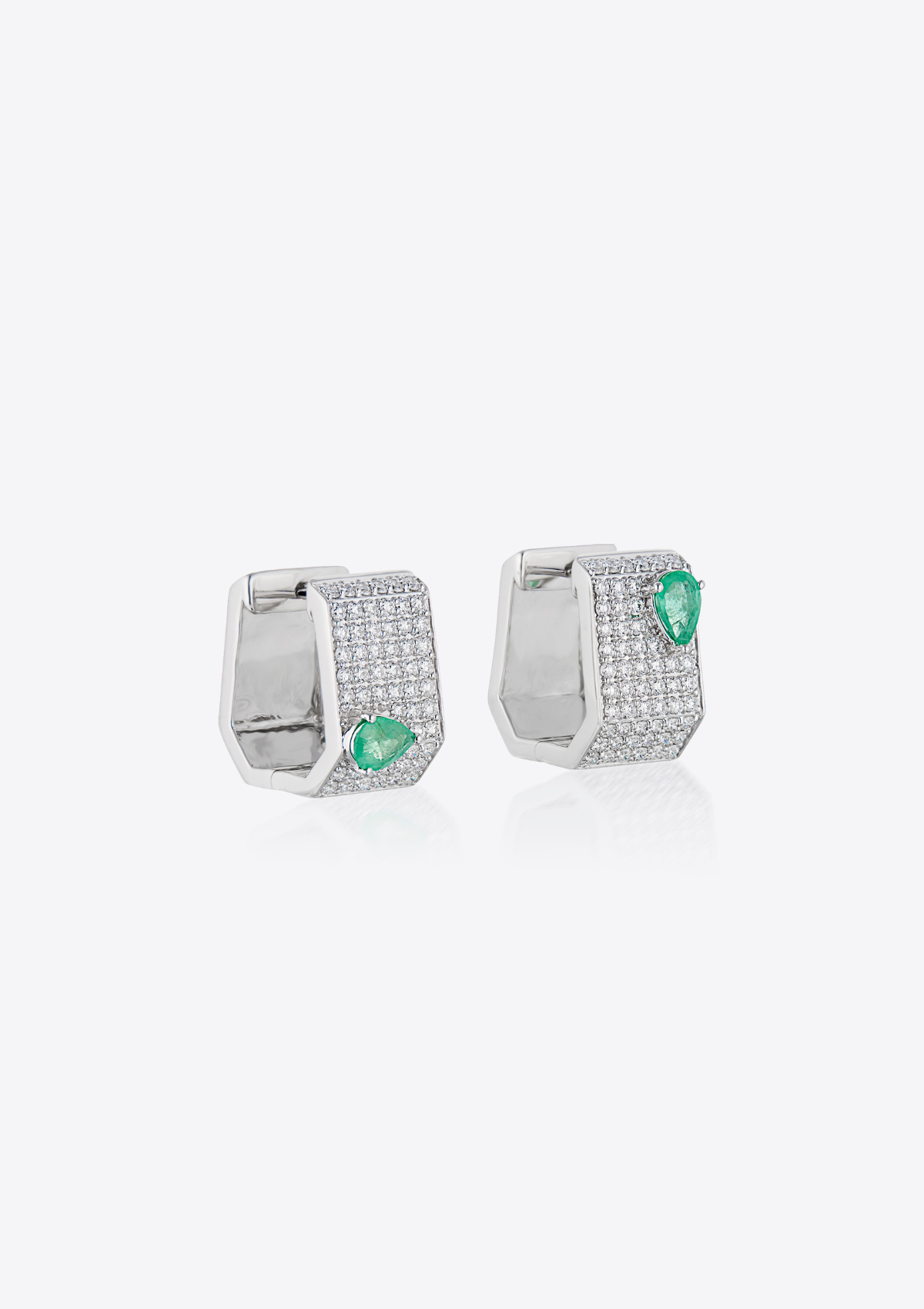 angled view of geometric diamond pave earrings with pear-shaped emeralds on a grey background
