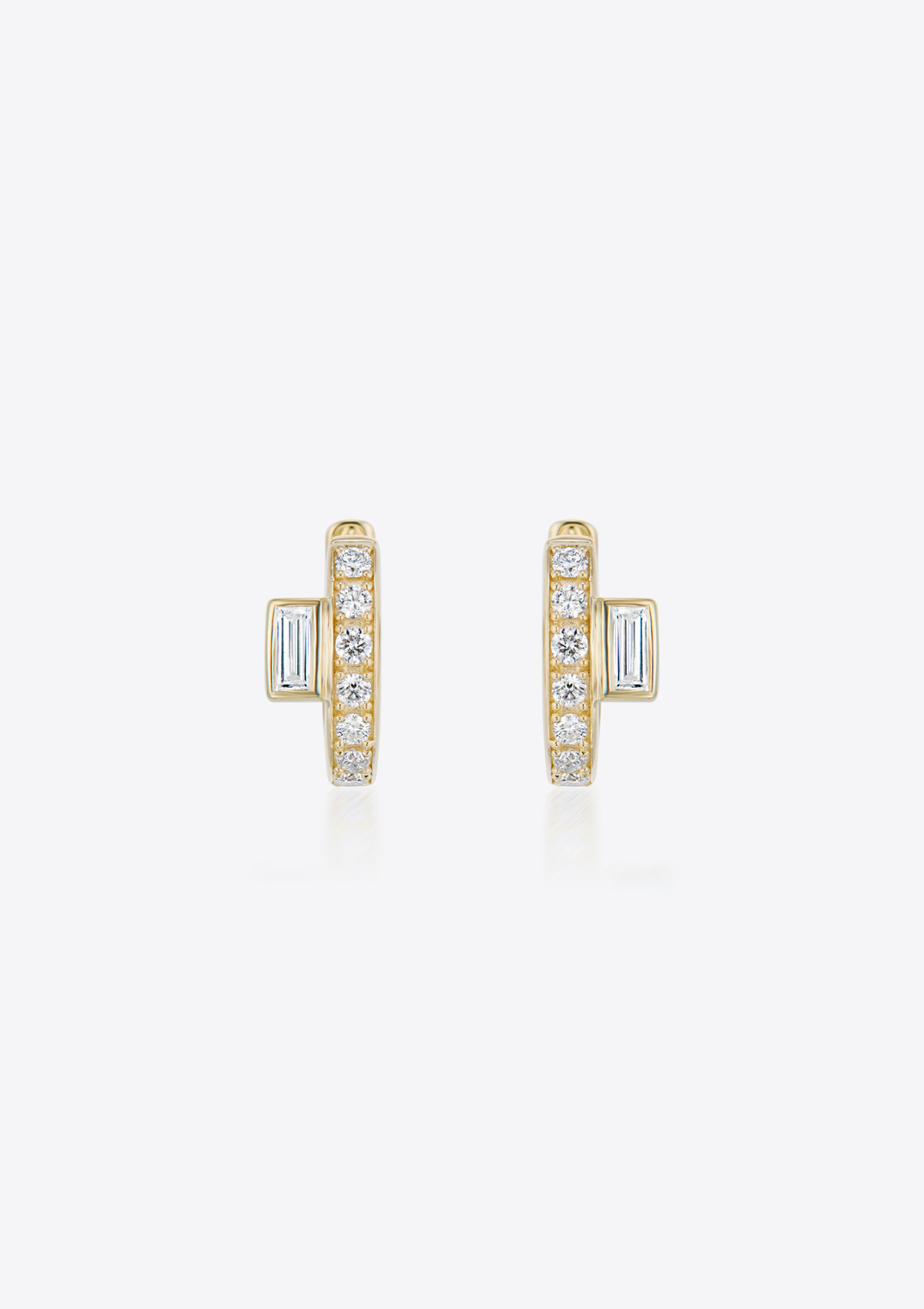Gold diamond huggie earrings with baguette diamonds placed off-centre on a grey background