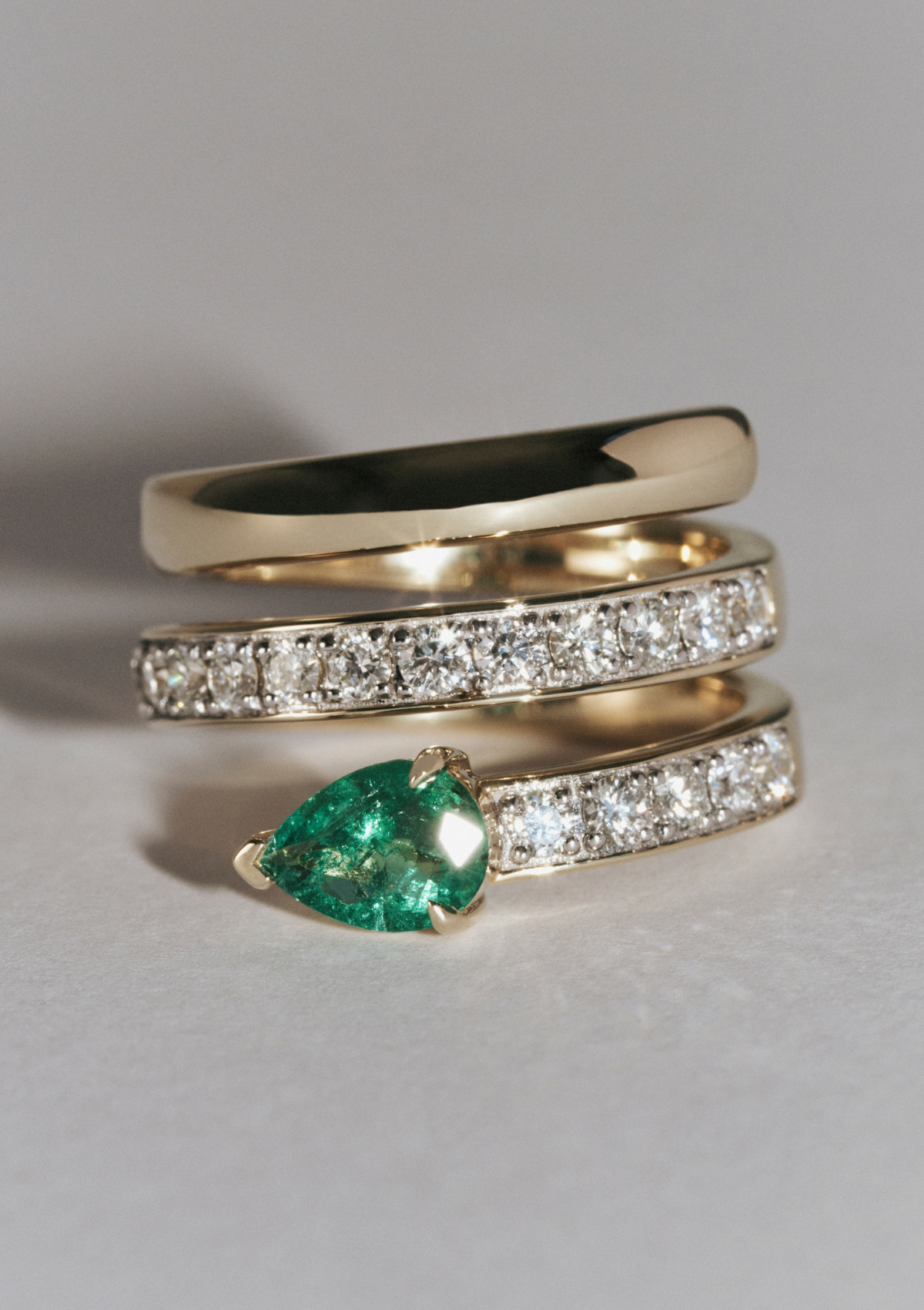 Yellow gold ring with small diamonds and a pear-shaped emerald sparkling in the light