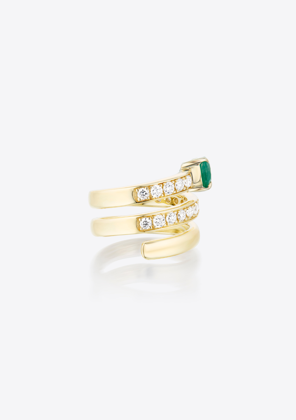 Side view of yellow gold coil ring with small diamonds and a pear-shaped emerald on a grey background